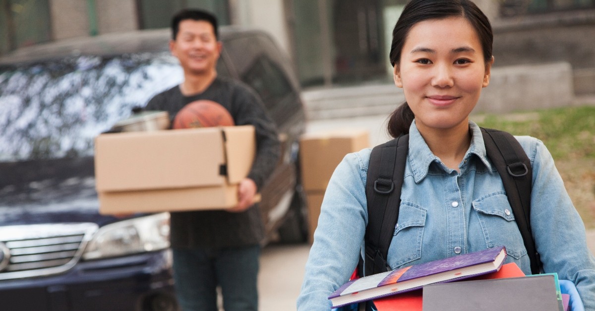 adult child holding packing boxes leaving for college, empty nester