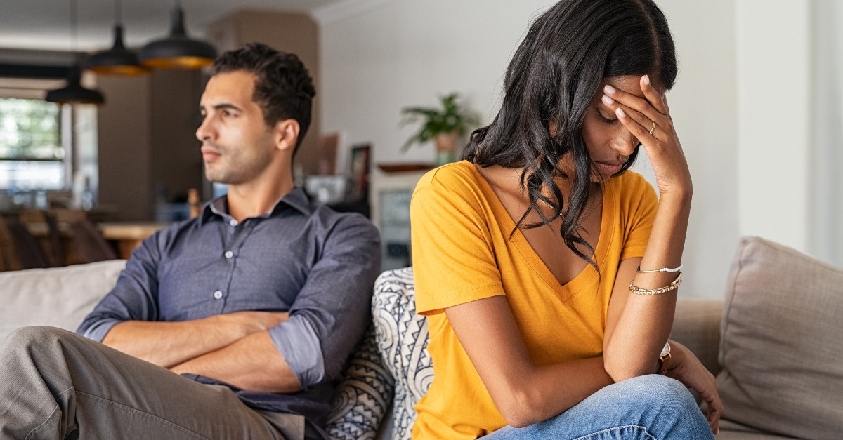 wife and husband upset with each other sitting on couch