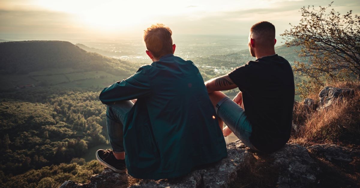 two guy friends sitting on mountain men boys