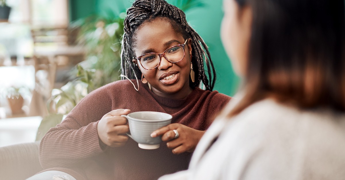 Women friends having coffee talking on couch