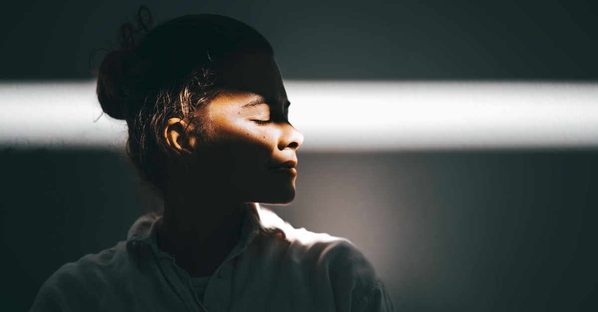 Woman standing with a beam of light across her face